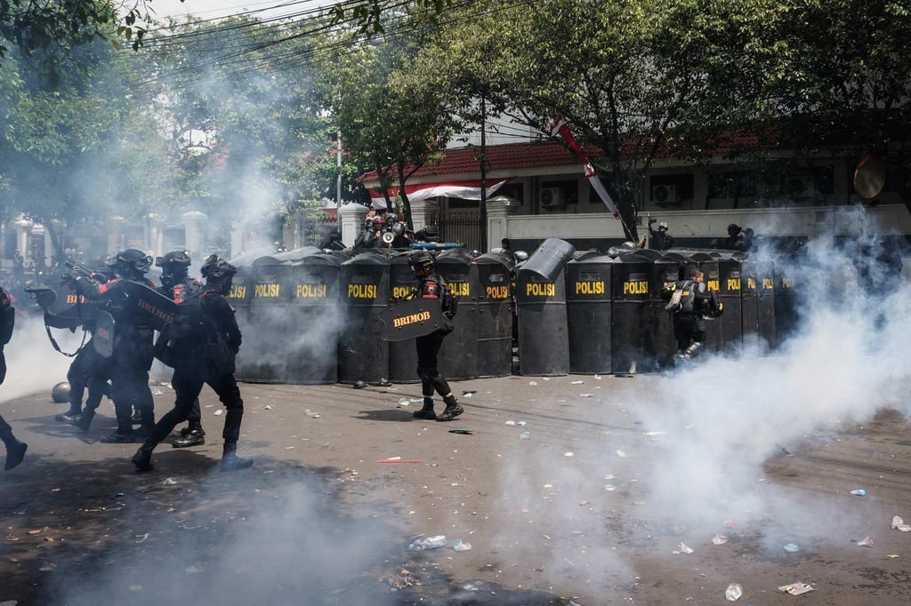 Police officers take cover as they release tear gas during a protest against a steep increase in the urban and rural land and building tax, known as PBB-P2, in Pati, Central Java, on August 13. Photo: AFP