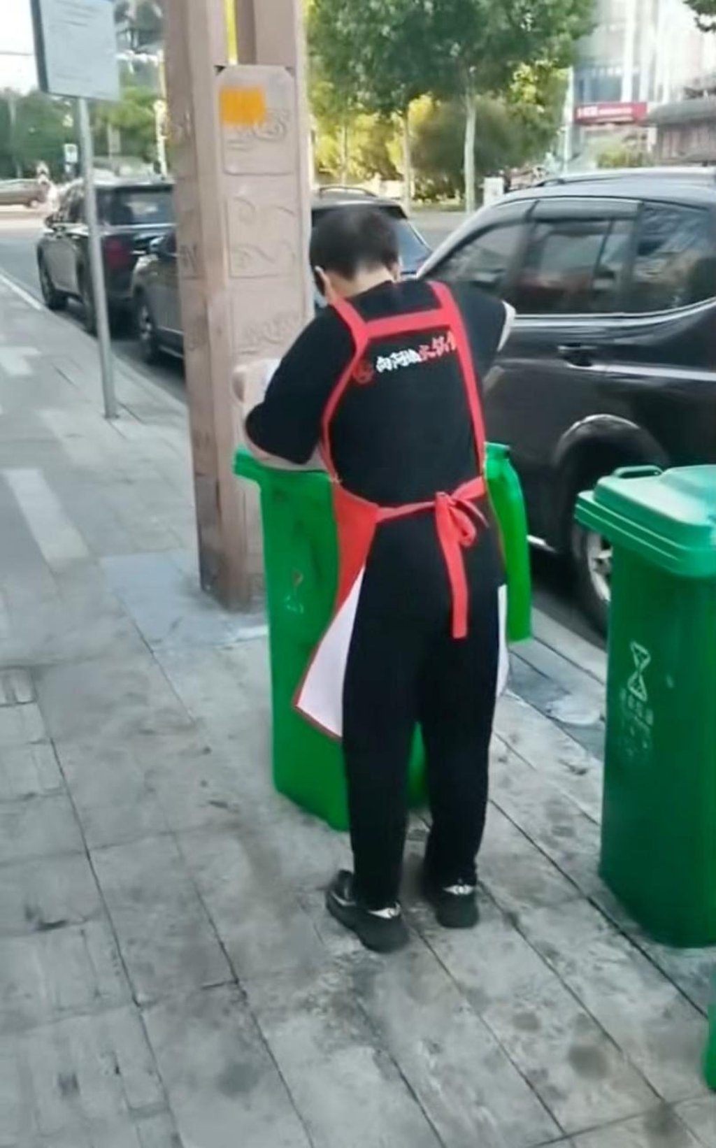 The woman worker was filmed scooping the oil into a bowl from a roadside bin. Photo: Handout The woman worker was filmed scooping the oil into a bowl from a roadside bin. Photo: Handout