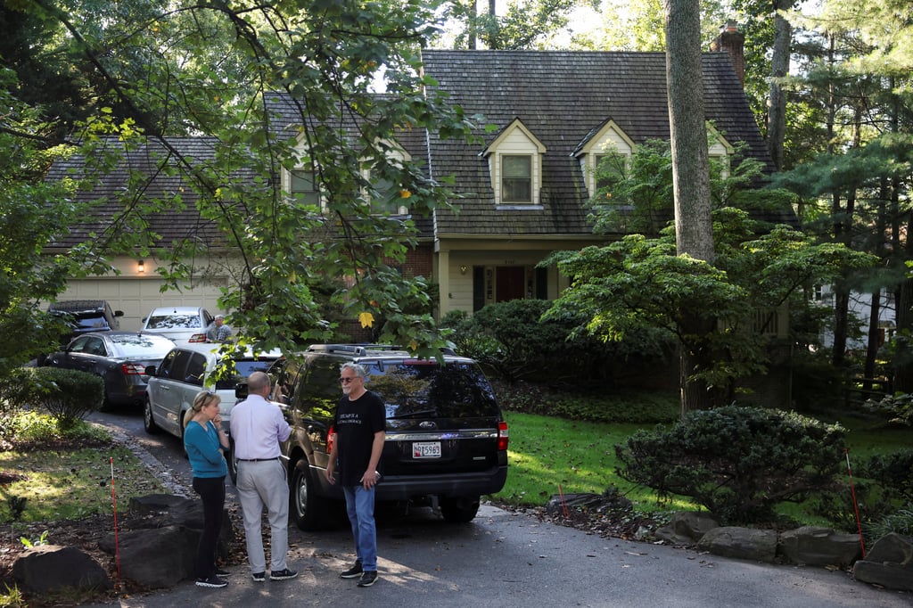 People stand outside the home of the former White House national security adviser John Bolton as it is searched by the US law enforcement agency in Bethesda, Maryland on Friday. Photo: Reuters People stand outside the home of the former White House national security adviser John Bolton as it is searched by the US law enforcement agency in Bethesda, Maryland on Friday. Photo: Reuters