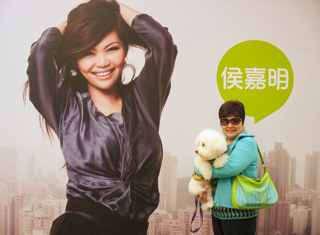Alyson Hau’s mother and Baychu the dog in front of a billboard of Hau promoting the Morning Suite show on Radio 2. Photo: courtesy Alyson Hau