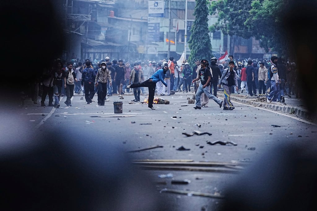 Protesters throw rocks towards riot police during a protest in Jakarta, Indonesia on Monday calling for a salary cut for parliamentarians. Photo: AP Protesters throw rocks towards riot police during a protest in Jakarta, Indonesia on Monday calling for a salary cut for parliamentarians. Photo: AP
