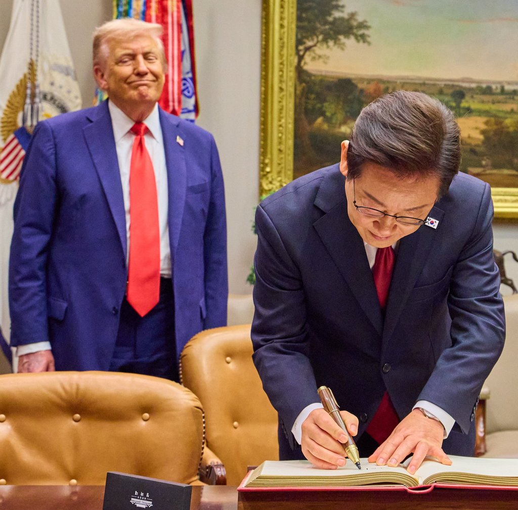 South Korean President Lee Jae-myung (right) signs the White House guest book on Monday as US President Donald Trump looks. Photo: EPA/Yonhap