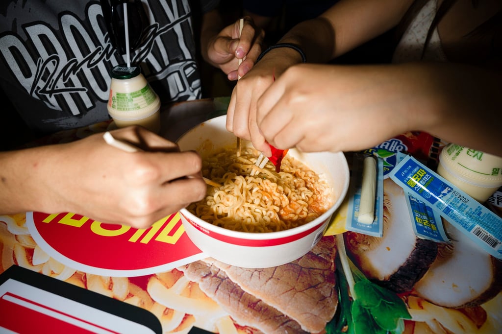 Two teenagers mix a bowl of Buldak Samyang instant noodles in the Hongdae district of Seoul, South Korea. Photo: Getty Images