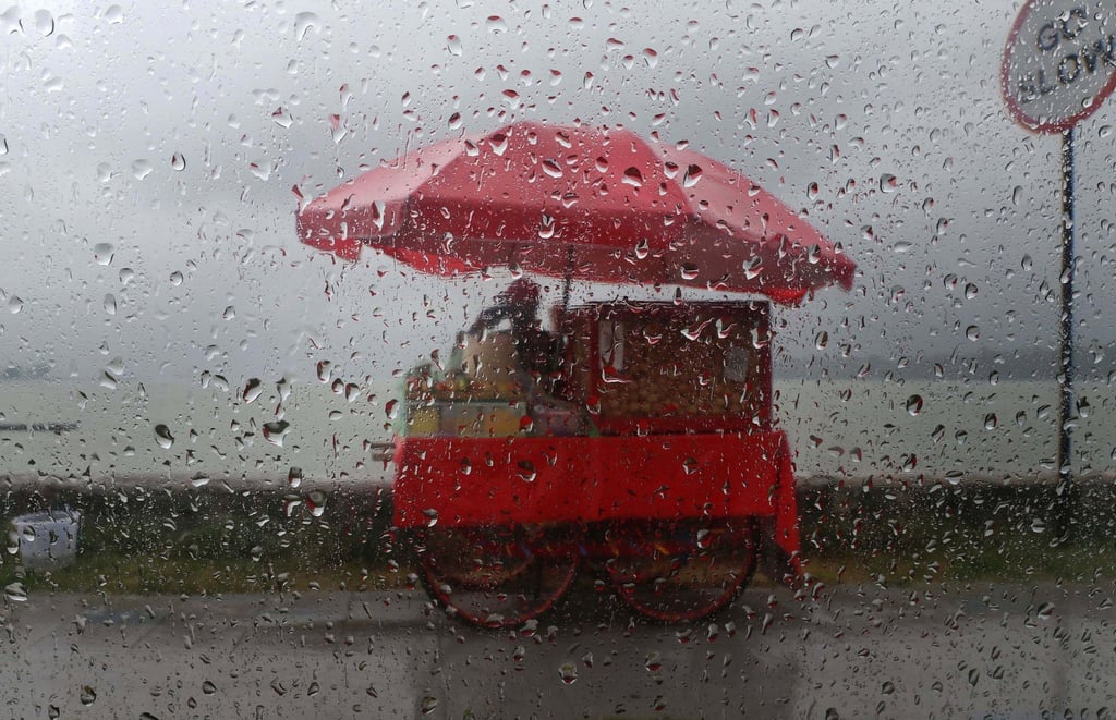 epa12307903 A photo taken from the windscreen of a car shows a roadside vendor waiting for customers during rainfall in Srinagar, India, earlier this month. Photo: EPA epa12307903 A photo taken from the windscreen of a car shows a roadside vendor waiting for customers during rainfall in Srinagar, India, earlier this month. Photo: EPA