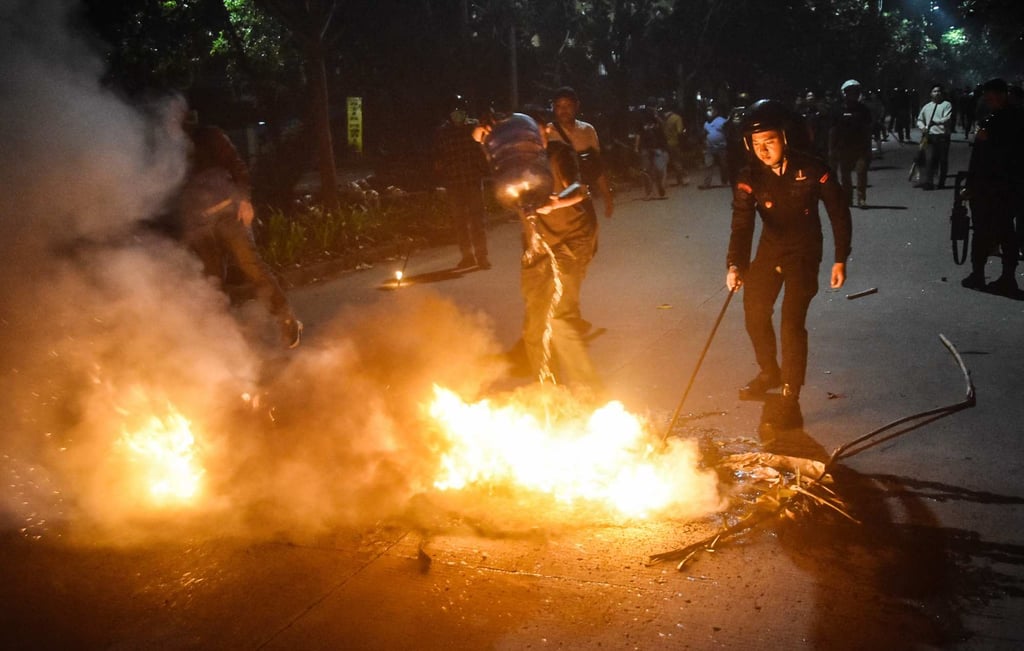 Police officers put out a fire set by protesters in front of the Bekasi Metro Police headquarters in West Java on Monday. Photo: AFP Police officers put out a fire set by protesters in front of the Bekasi Metro Police headquarters in West Java on Monday. Photo: AFP