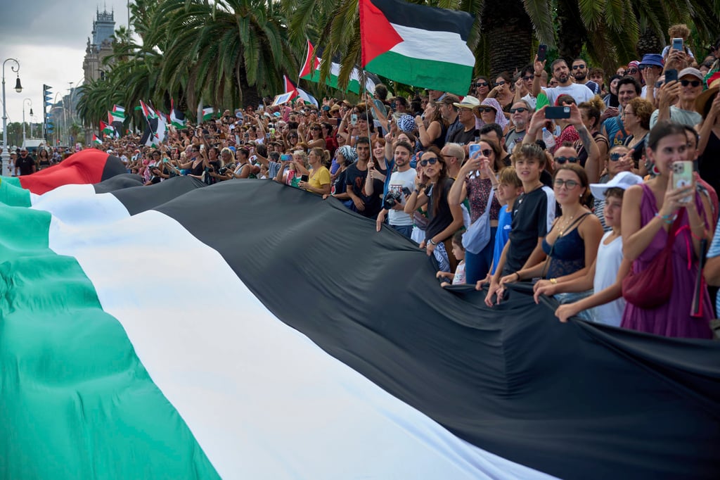 People hold Palestinian flags as they bid farewell to activists setting sail on their boats. Photo: AP People hold Palestinian flags as they bid farewell to activists setting sail on their boats. Photo: AP
