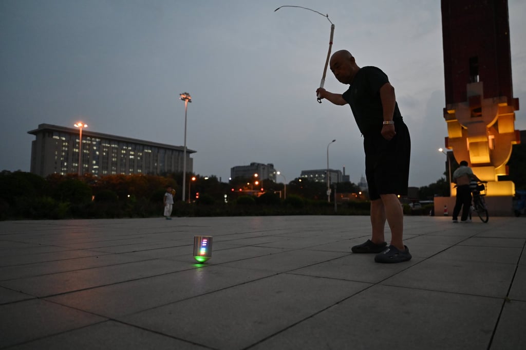 Mr Wang swings a whip to drive a colourful spinning top in a park near Beijing’s Olympic Centre. Photo: dpa