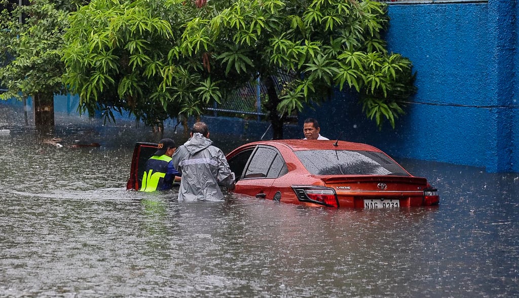 People push a car that has been partially submerged in floodwater during heavy rain in Quezon City on Saturday. Photo: Xinhua People push a car that has been partially submerged in floodwater during heavy rain in Quezon City on Saturday. Photo: Xinhua