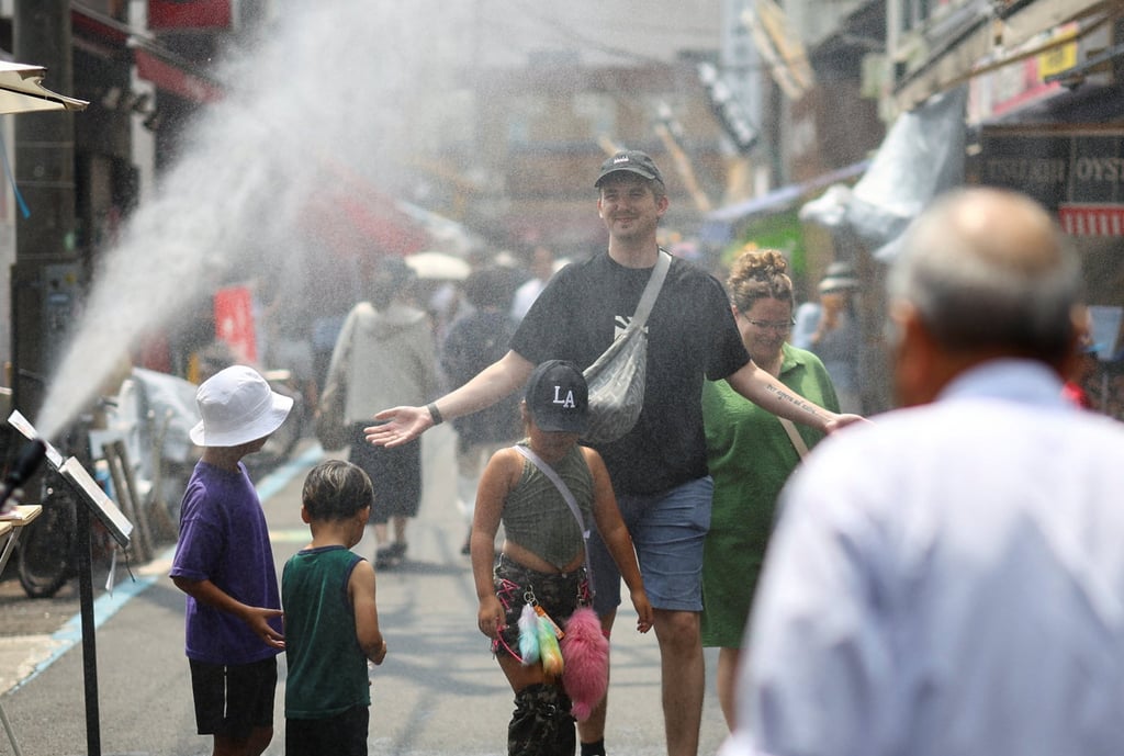 Foreign tourists walk through a cooling mist amid a heatwave in Tokyo late last month. Photo: Reuters Foreign tourists walk through a cooling mist amid a heatwave in Tokyo late last month. Photo: Reuters