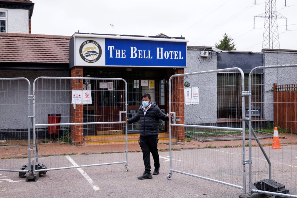A staff member closes the gate outside The Bell Hotel in Epping, Essex. Photo: EPA A staff member closes the gate outside The Bell Hotel in Epping, Essex. Photo: EPA