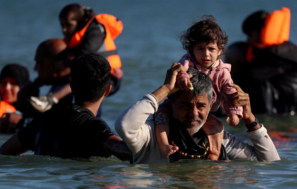 Migrants wade through the sea to board an inflatable dinghy leaving the coast of northern France to cross the English Channel on August 25. Photo: Reuters Migrants wade through the sea to board an inflatable dinghy leaving the coast of northern France to cross the English Channel on August 25. Photo: Reuters