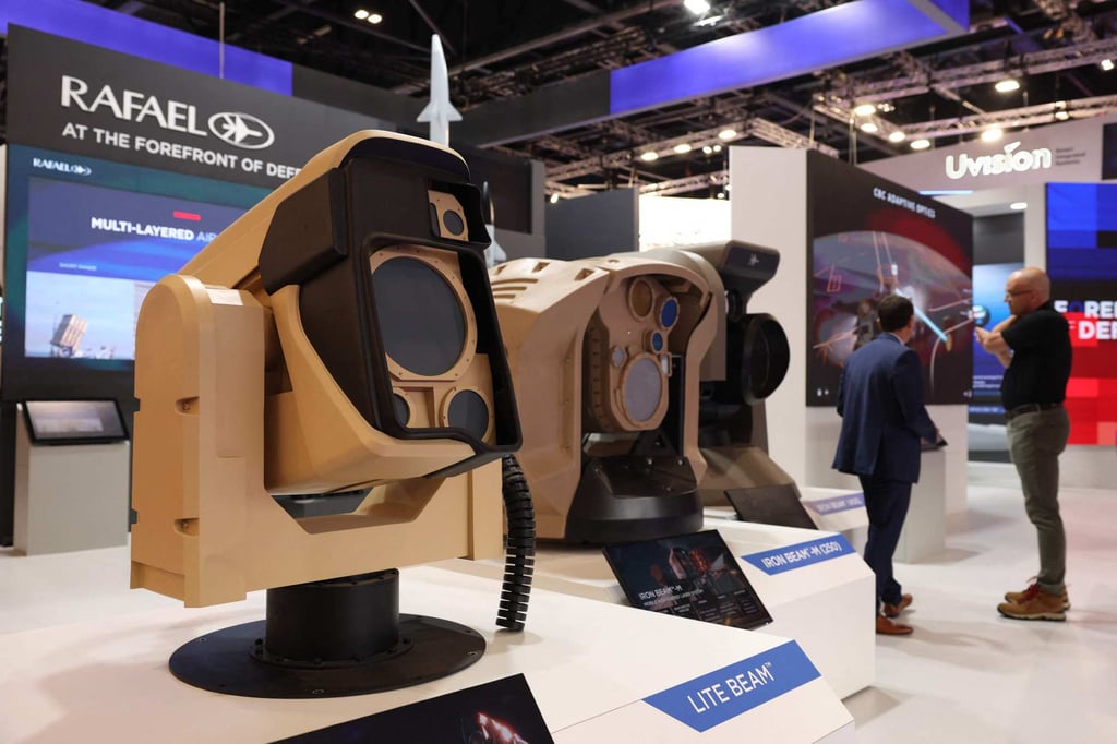Delegates talk near the Rafael stand with a Lite Beam laser-based defense system on display at the Defence and Security Equipment International fair at the ExCeL centre, in east London, on Tuesday. Photo: AFP