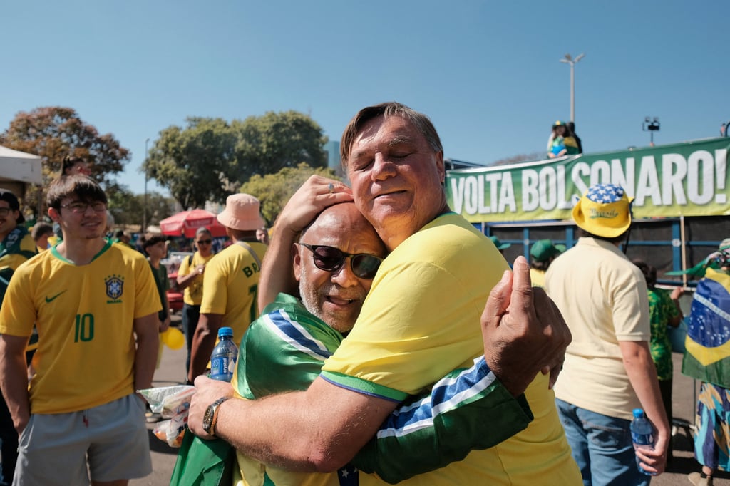 Uber driver Alessandro Almeida, a Bolsonaro supporter known for his resemblance to the Brazilian ex-president, embraces another man during a protest in Brasilia on Sunday. Photo: Reuters Uber driver Alessandro Almeida, a Bolsonaro supporter known for his resemblance to the Brazilian ex-president, embraces another man during a protest in Brasilia on Sunday. Photo: Reuters
