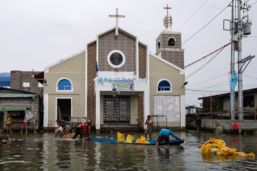 Workers unload sandbags at a construction site outside a church on a flooded street on Isla Pugad in Hagonoy town, Bulacan province, north of Manila, on August 21. Photo: AFP