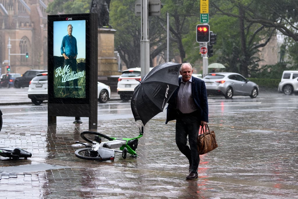 A man walks through heavy rain in Sydney last month as an unpredictable, widespread weather system hit Australia’s east coast. Photo: EPA