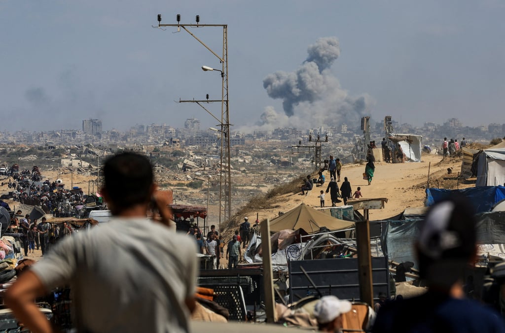 Smoke rises from an Israeli strike, as displaced Palestinians, fleeing northern Gaza due to an Israeli military operation, head south on Tuesday. Photo: Reuters