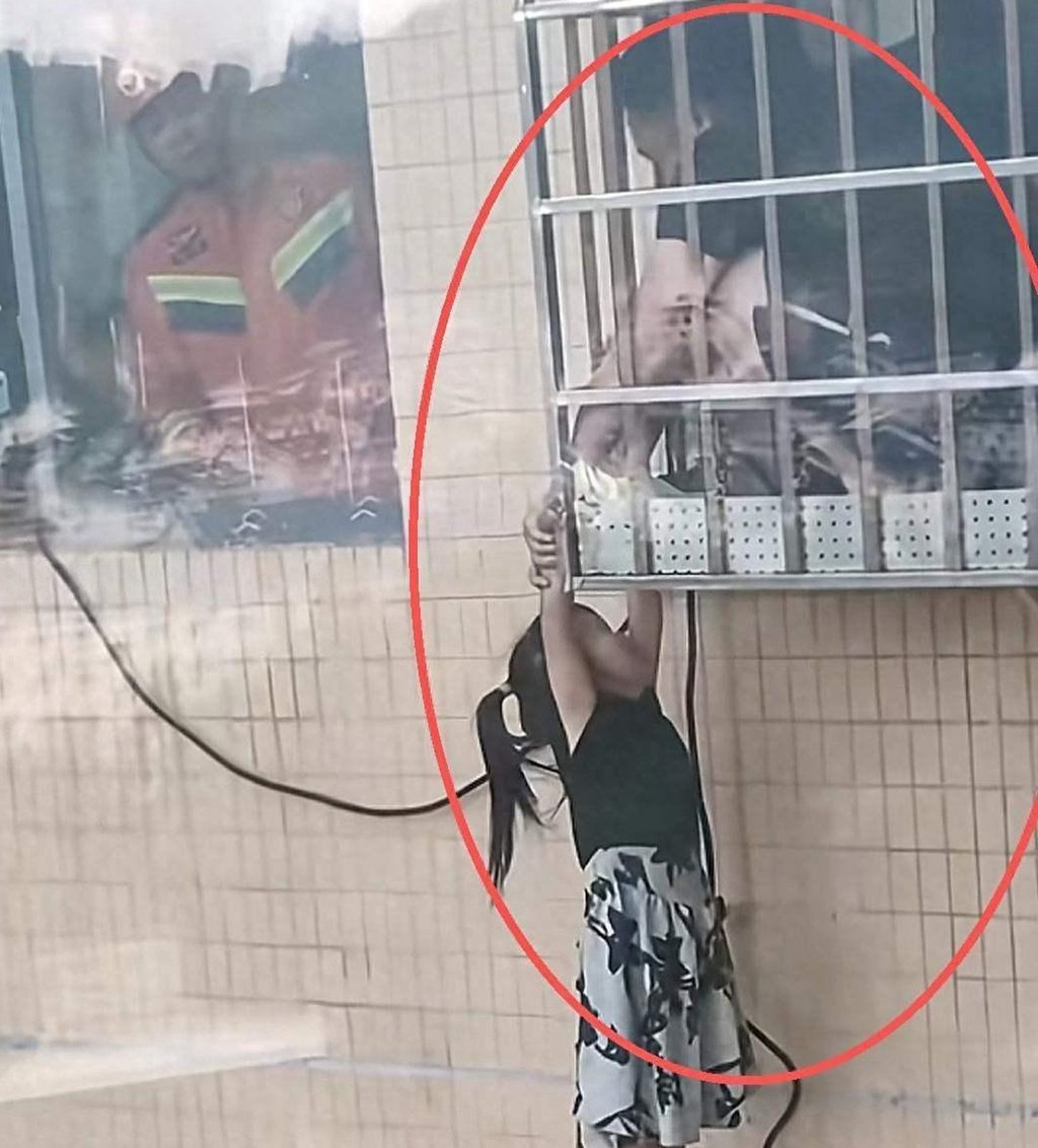 The little girl hangs on for dear life as her neighbour holds on to her tightly. Photo: Handout