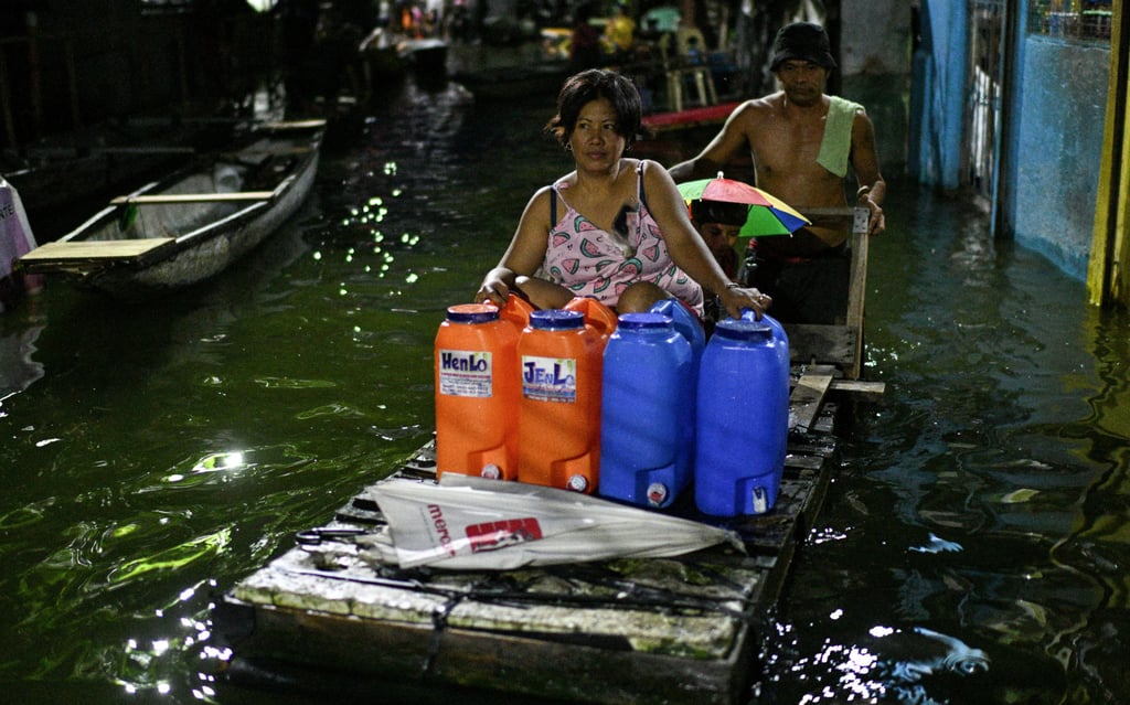 A woman rides on a makeshift raft to cross a flooded street following rains from Tropical Storm Bualoi in Dela Paz, Philippines, on Friday. Photo: Reuters
