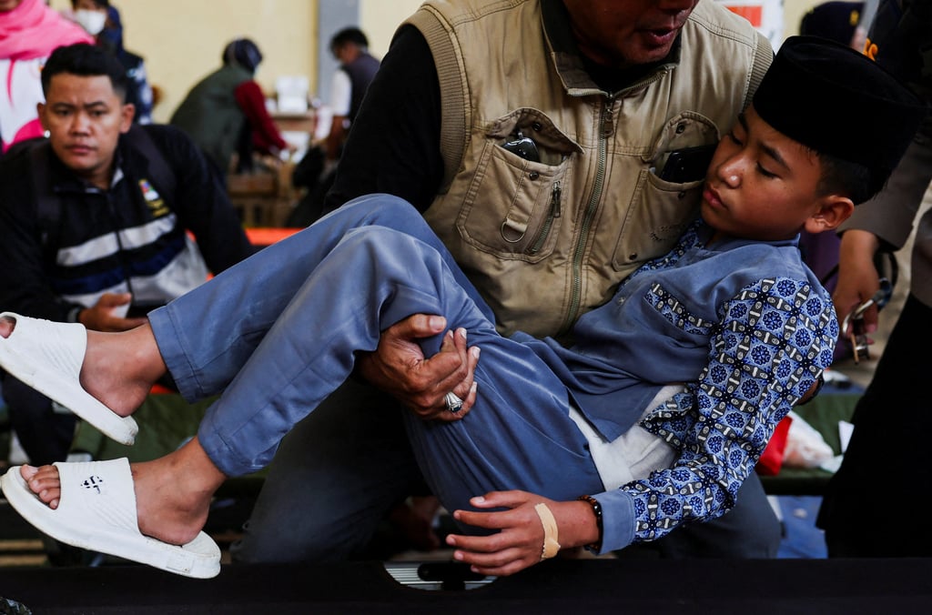 An officer carries a 13-year-old student suffering from food poisoning after eating government-sponsored free school meals at a makeshift clinic in Bandung, Indonesia, on Thursday. Photo: Reuters