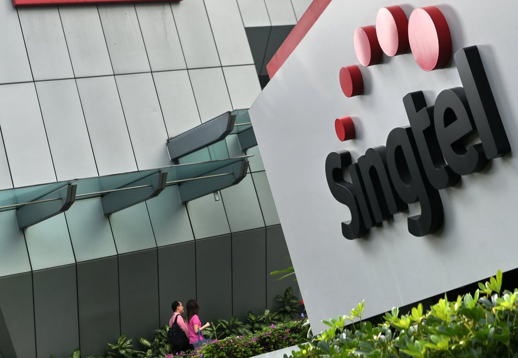 A couple walks towards the Singtel building in Singapore. Singtel owns Optus, Australia’s No 2 telecoms company. Photo: AFP