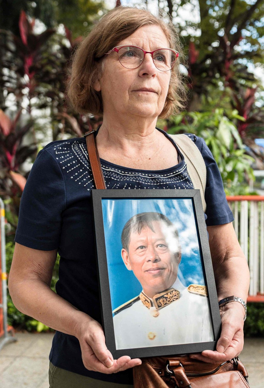 Anne-Marie Lim, widow of former Cambodian opposition lawmaker Lim Kimya, holds a picture of her late husband as she arrives for the Criminal Court trial on Tuesday. Photo: AFP