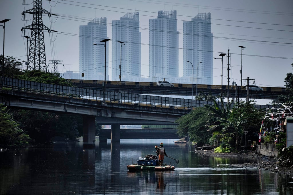 Workmen clear rubbish from standing water trapped in a low-lying neighbourhood of Jakarta. Photo: Getty Images Workmen clear rubbish from standing water trapped in a low-lying neighbourhood of Jakarta. Photo: Getty Images