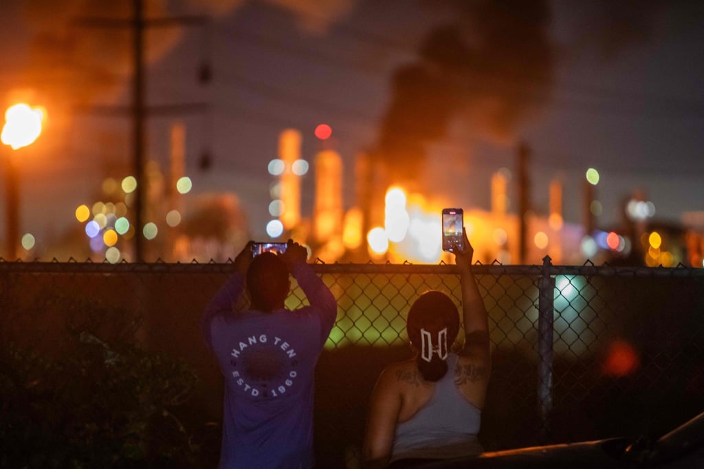 People in Manhattan beach take pictures as a fire burns at a Chevron refinery on Thursday in El Segundo, California. Photo: via AFP