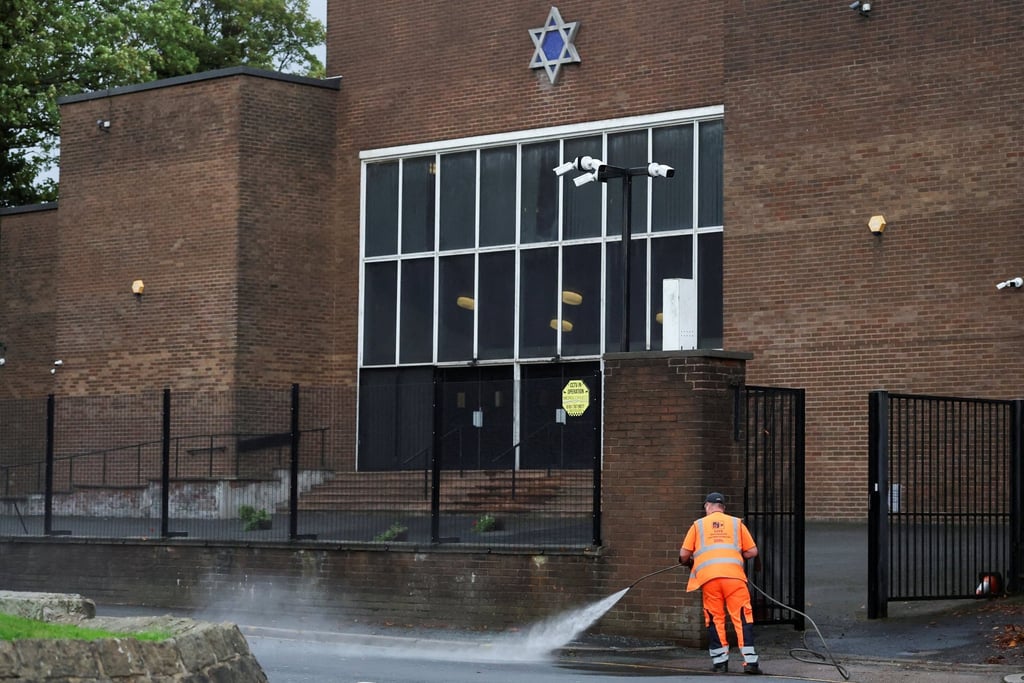 A worker cleans in front of the Manchester synagogue, where people were killed last Thursday. Photo: Reuters