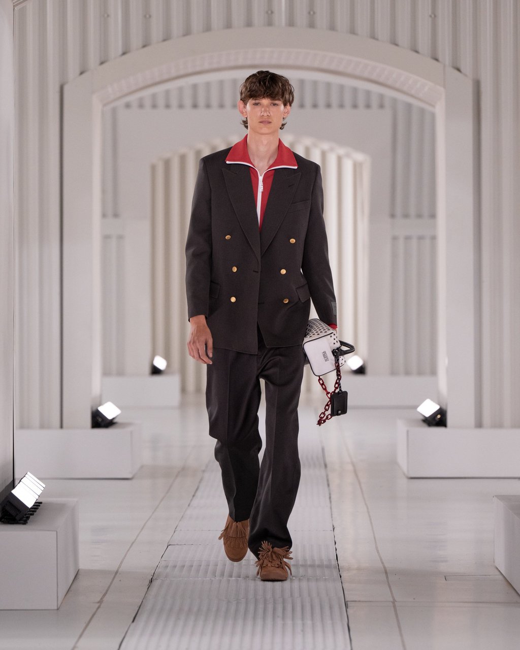 Brown and black come together again in a double-breasted black blazer and trousers, worn over a sporty red zip-collar top, with textured brown shoes. Photo: Handout