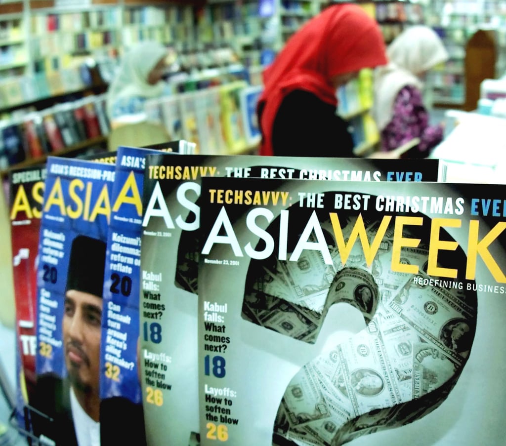Women read books behind the “Asiaweek” magazines on display at a bookshop in Kuala Lumpur in November 2001. Photo: AP