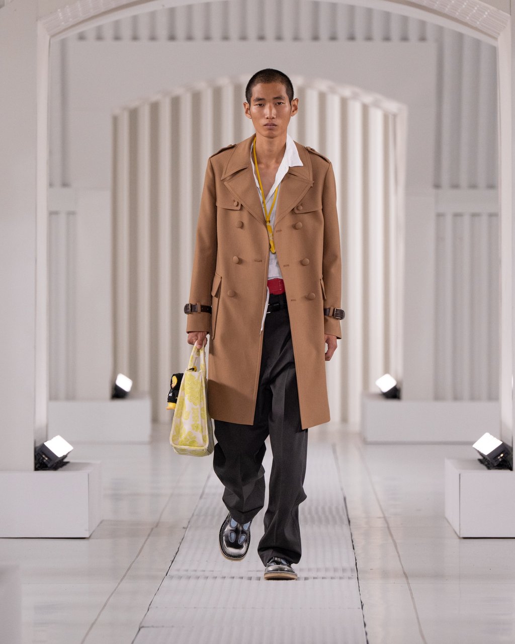 Casual yet polished: a camel trench coat, relaxed black trousers and bright patterned tote at Onitsuka Tiger. Photo: Handout