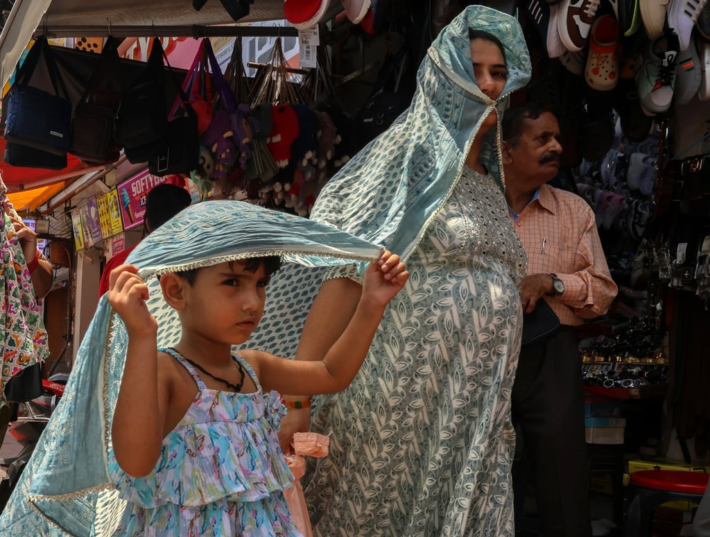 People in the old quarter of Delhi cover themselves with fabric to avoid the sun during a hot day in June. Photo: EPA-EFE