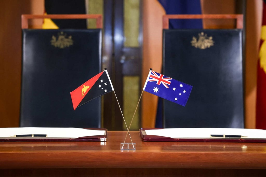 The flags of Australia and Papua New Guinea are displayed on a desk at Parliament House in Canberra on Monday. Photo: AFP