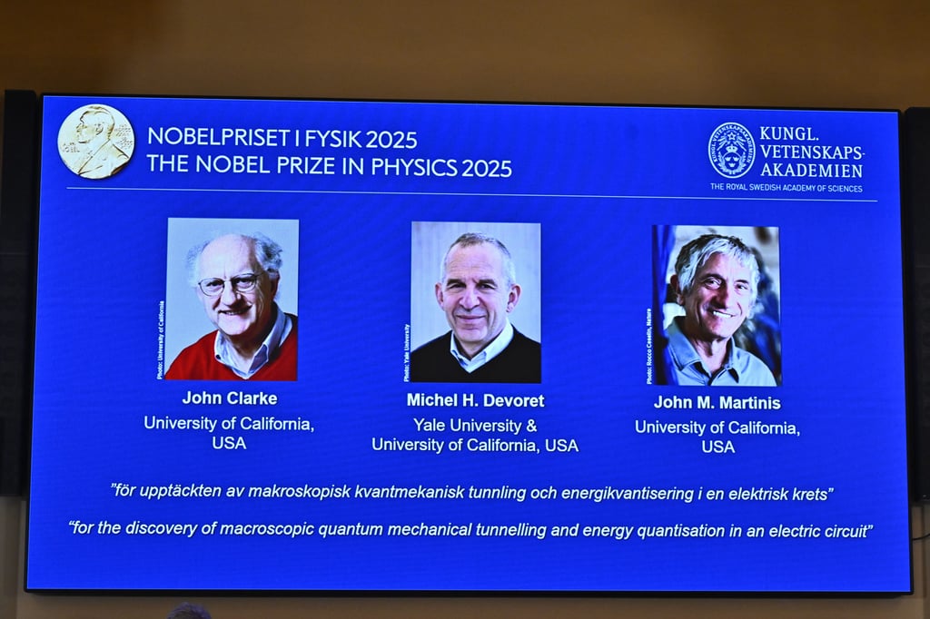 Photos of John Clarke, Michel Devoret and John Martinis are pictured on a screen after they were announced as winners of the Nobel Prize in Physics in Stockholm, Sweden on Tuesday. Photo: TT News Agency/AP
