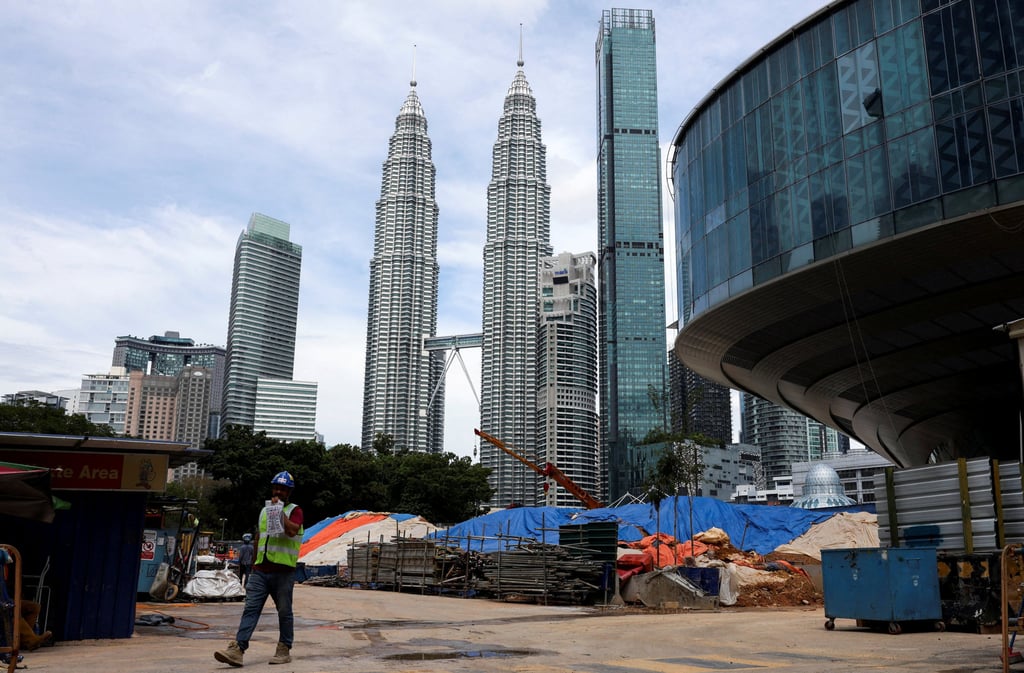 A worker walks out of a construction site, next to the Petronas Twin Towers on Friday. Malaysia plans to spend 470 billion ringgit to boost infrastructure, expand rural digital access and help youth boost their income. Photo: Reuters