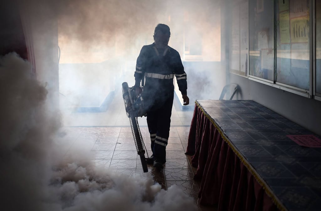 A pest-control worker fumigates a Kuala Lumpur classroom before the Primary School Evaluation Test, following Malaysia’s first local Zika case in 2016. Schools nationwide are being urged to take measures against influenza. Photo: AFP