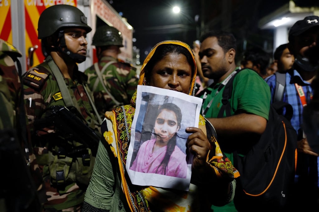 A relative mourns while holding a picture of a missing girl following a fire that broke out at a garment factory and a chemical warehouse in Dhaka, Bangladesh, on Tuesday. Photo: Reuters