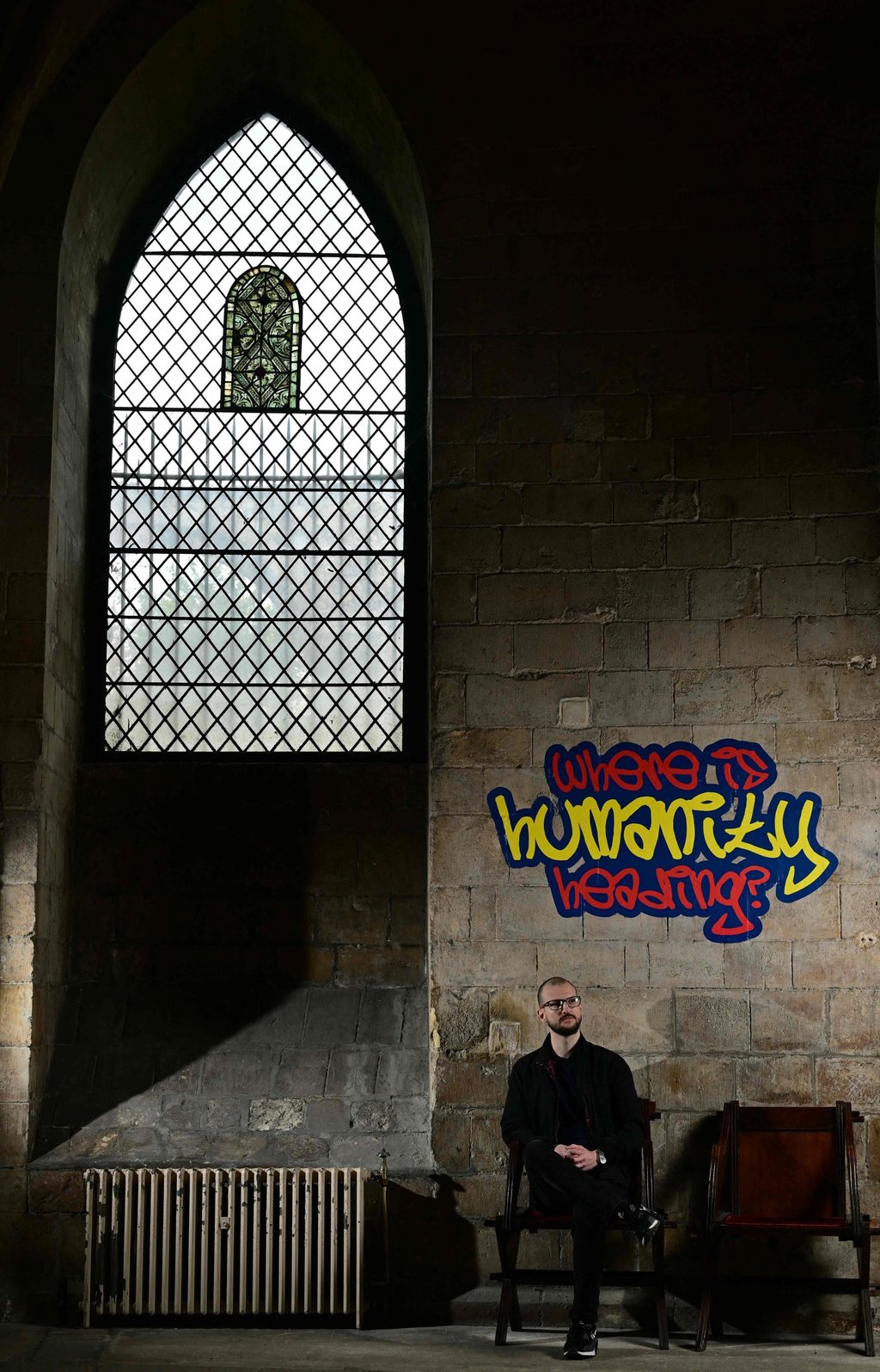Poet Alex Vellis poses inside Canterbury Cathedral in Canterbury, southeast England, where graffiti-style artworks posing the questions of ordinary people to God are displayed. Photo: AFP Poet Alex Vellis poses inside Canterbury Cathedral in Canterbury, southeast England, where graffiti-style artworks posing the questions of ordinary people to God are displayed. Photo: AFP