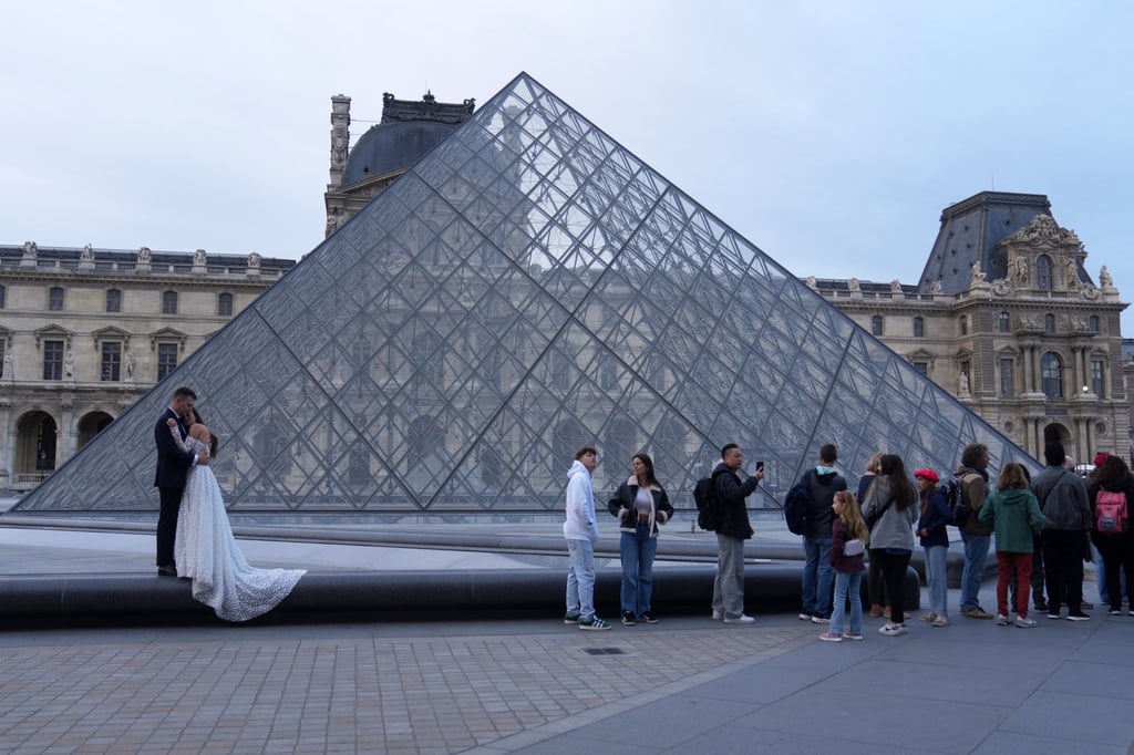 A wedding couple hugs as visitors queue to enter the Louvre museum three days after historic jewels were stolen in a daring daylight heist, on October 22, in Paris. Photo: AP Photo