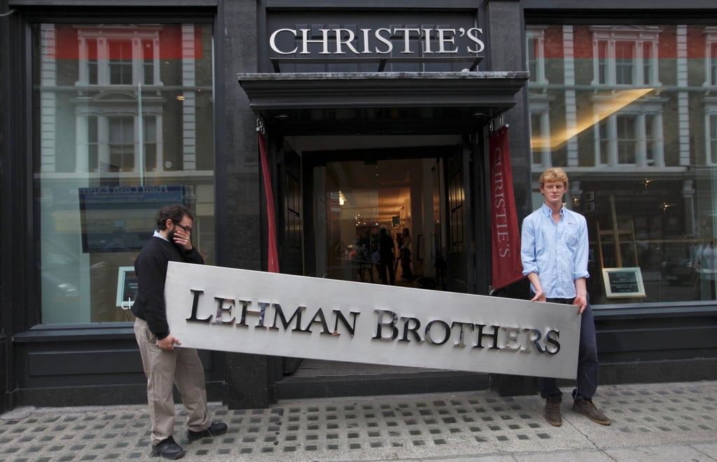 Christie’s employees pose with a Lehman Brothers sign at the auction house in central London on September 24, 2010. Photo: Reuters