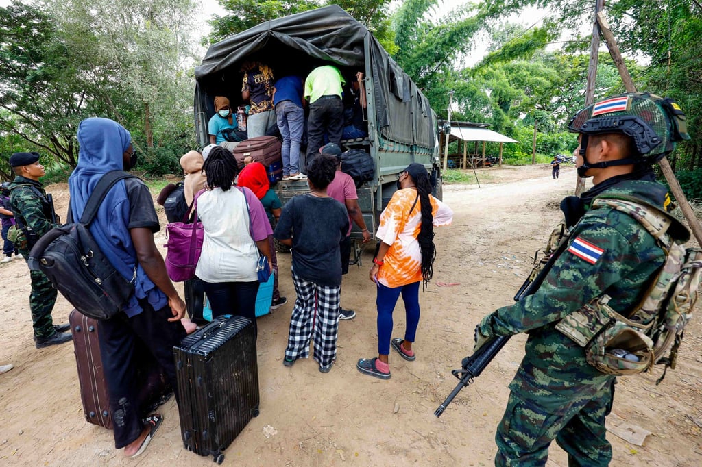 People from various countries who were working in the KK Park compound in Myanmar and crossed to Thailand via the Moei river, board a vehicle as Thai soldiers keep watch. Photo: Thai News Pix/AFP