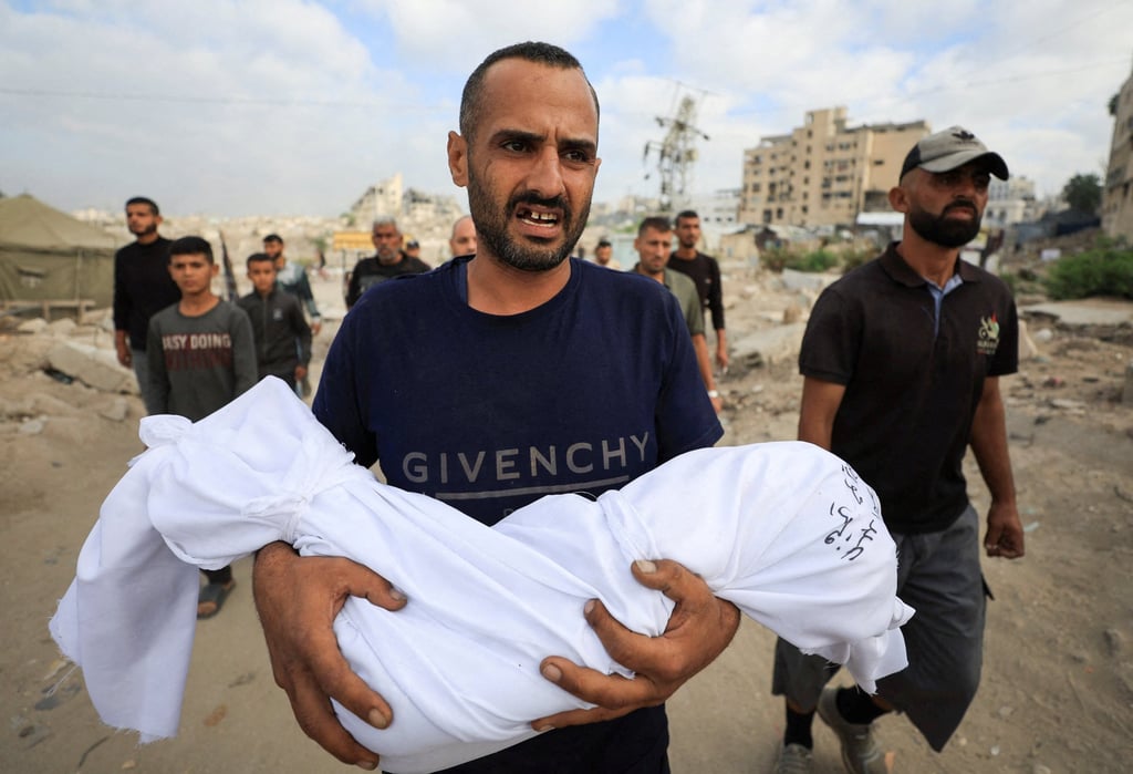 A man carries the body of a child after overnight Israeli strikes. Photo: Reuters A man carries the body of a child after overnight Israeli strikes. Photo: Reuters