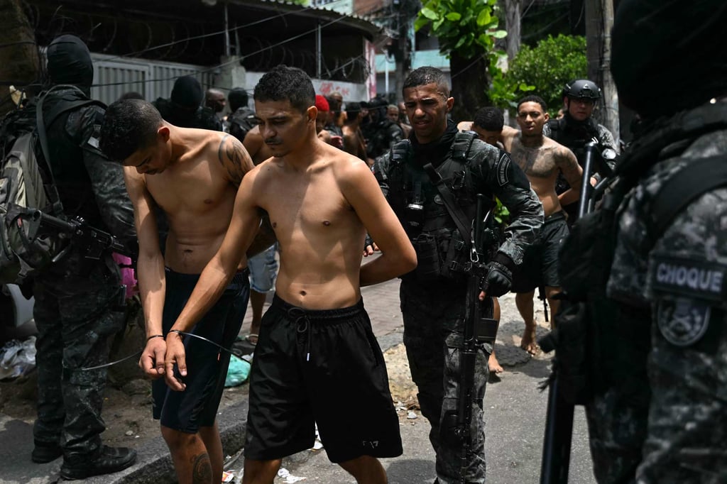 Police officers escort alleged criminals arrested during Operacao Contencao in Rio de Janeiro, Brazil, on Tuesday. Photo: AFP