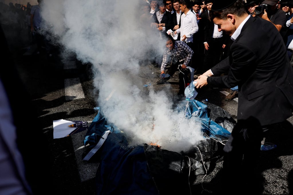 Ultra-Orthodox Jews pour water on burning material during a rally to protest against Israeli military conscription in Jerusalem on Thursday. Photo: Reuters Ultra-Orthodox Jews pour water on burning material during a rally to protest against Israeli military conscription in Jerusalem on Thursday. Photo: Reuters
