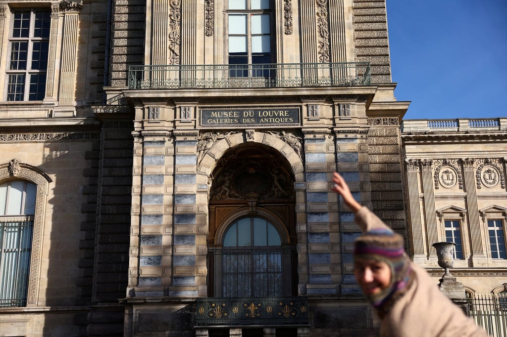 A person poses in front of an upstairs window that was broken by thieves to enter the Louvre museum. Photo: Reuters A person poses in front of an upstairs window that was broken by thieves to enter the Louvre museum. Photo: Reuters