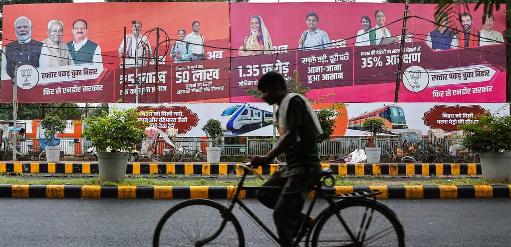 A cyclist rides past election banners displayed along a street in Patna on Saturday. Photo: AFP