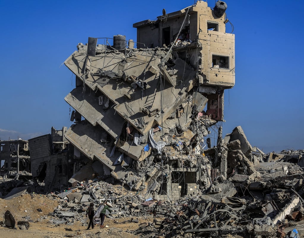 People stand in front of a destroyed building in Khan Younis, as displaced Palestinians return to their homes. Photo: dpa People stand in front of a destroyed building in Khan Younis, as displaced Palestinians return to their homes. Photo: dpa
