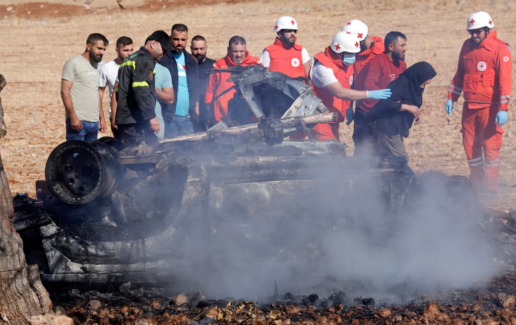 Members of the Lebanese Red Cross lead a grieving woman away from the smoking wreckage of a car struck by an Israeli drone in Shebaa on Saturday. Photo: EPA Members of the Lebanese Red Cross lead a grieving woman away from the smoking wreckage of a car struck by an Israeli drone in Shebaa on Saturday. Photo: EPA