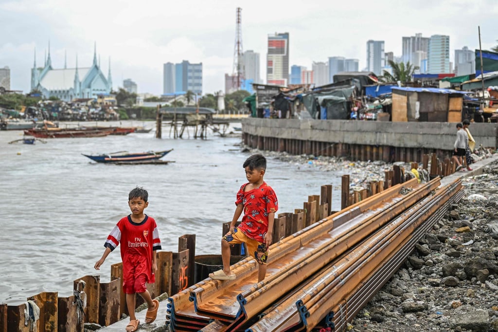 Children walk along a sea wall in Manila on Monday in the aftermath of Typhoon Fung-wong. Photo: AFP