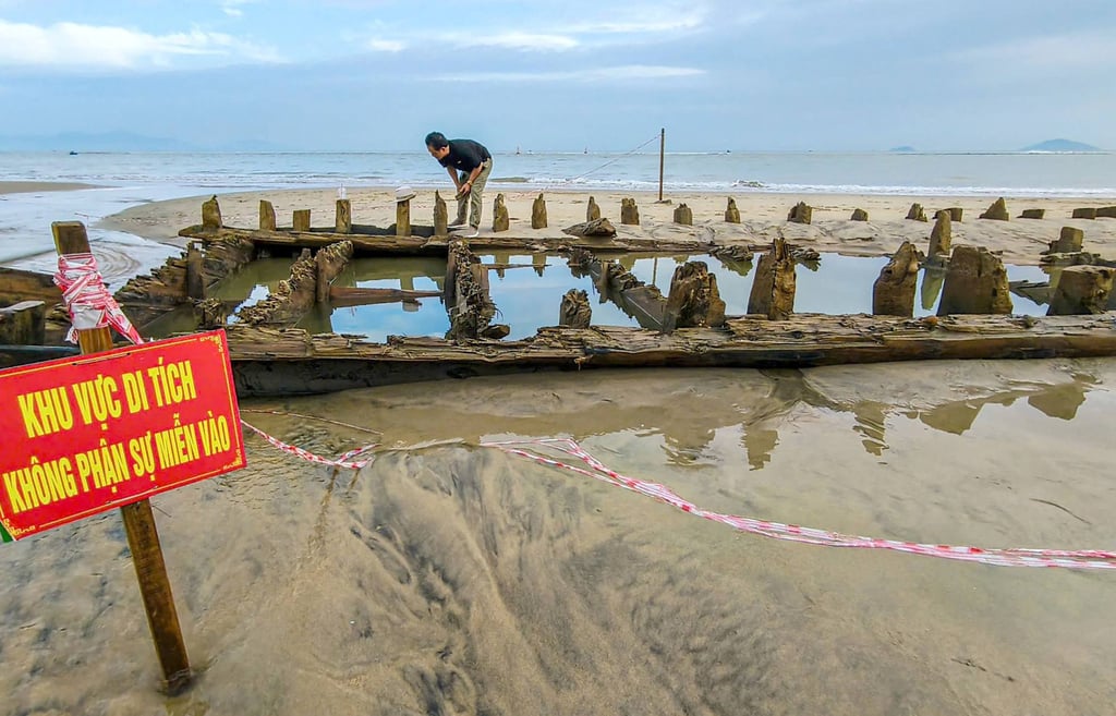 A man examines a centuries-old shipwreck uncovered on a Vietnamese beach after Typhoon Kalmaegi swept through the country. Photo: AFP
